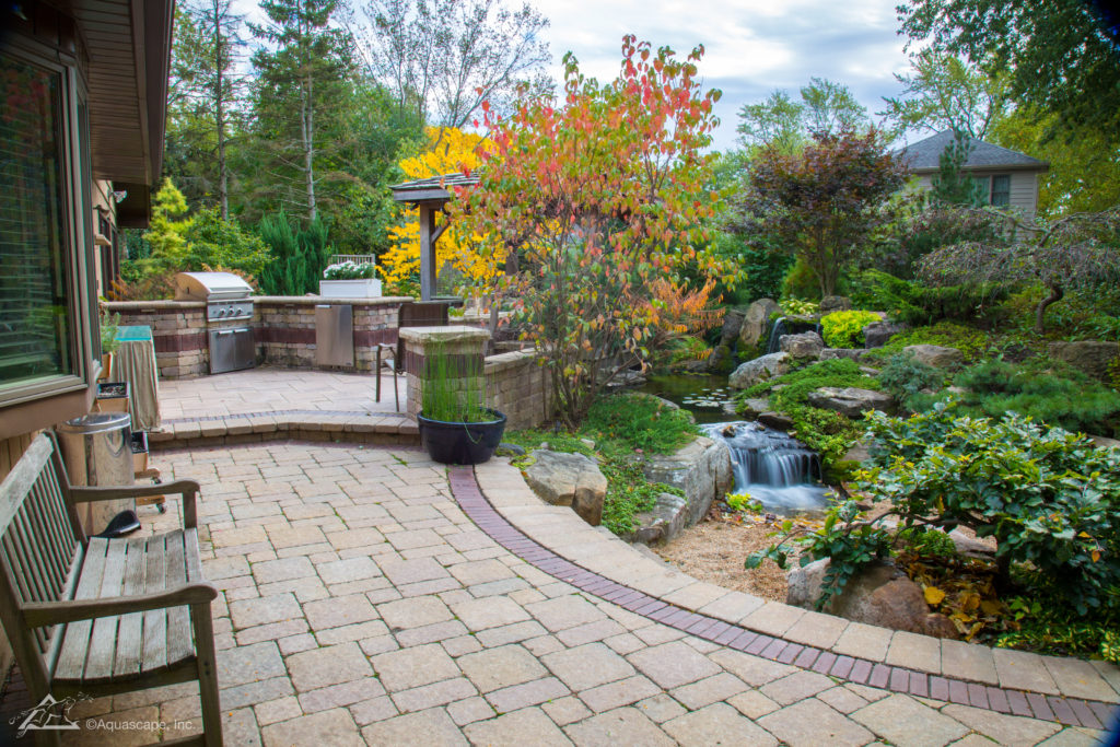 backyard pond with paver patio and outdoor kitchen